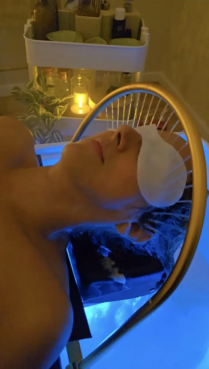 Una clienta descansa bajo el arco de agua durante un ritual Head Spa.