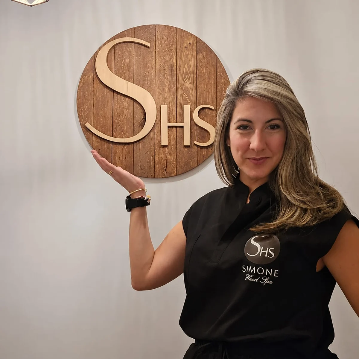 La especialista de Simone Head Spa junto al emblema de madera del centro.